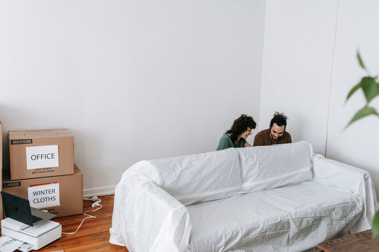Un couple savoure le déménagement dans leur nouvelle maison, entouré de cartons et d’un décor épuré.